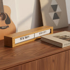 Preorder - Texttime 2.0 Bamboo Text Flip Clock on wood surface with book and guitar in background Dutch Design Functional Design