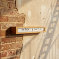 Preorder - Texttime 2.0 Bamboo Text Flip Clock with Dutch Design and Functional Design mounted on textured wall.