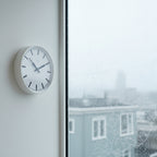 Factory White XL Clock minimalist wall clock in Dutch Design style with clean lines and functional design by the window on a rainy day