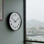 Factory Black XL Clock on wall near window with raindrops, minimalist modern clock showcasing Dutch Design, Functional Design style