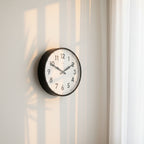 Factory Black XL Clock hanging on wall with natural light and shadows, Dutch Design, Functional Design, modern clocks.