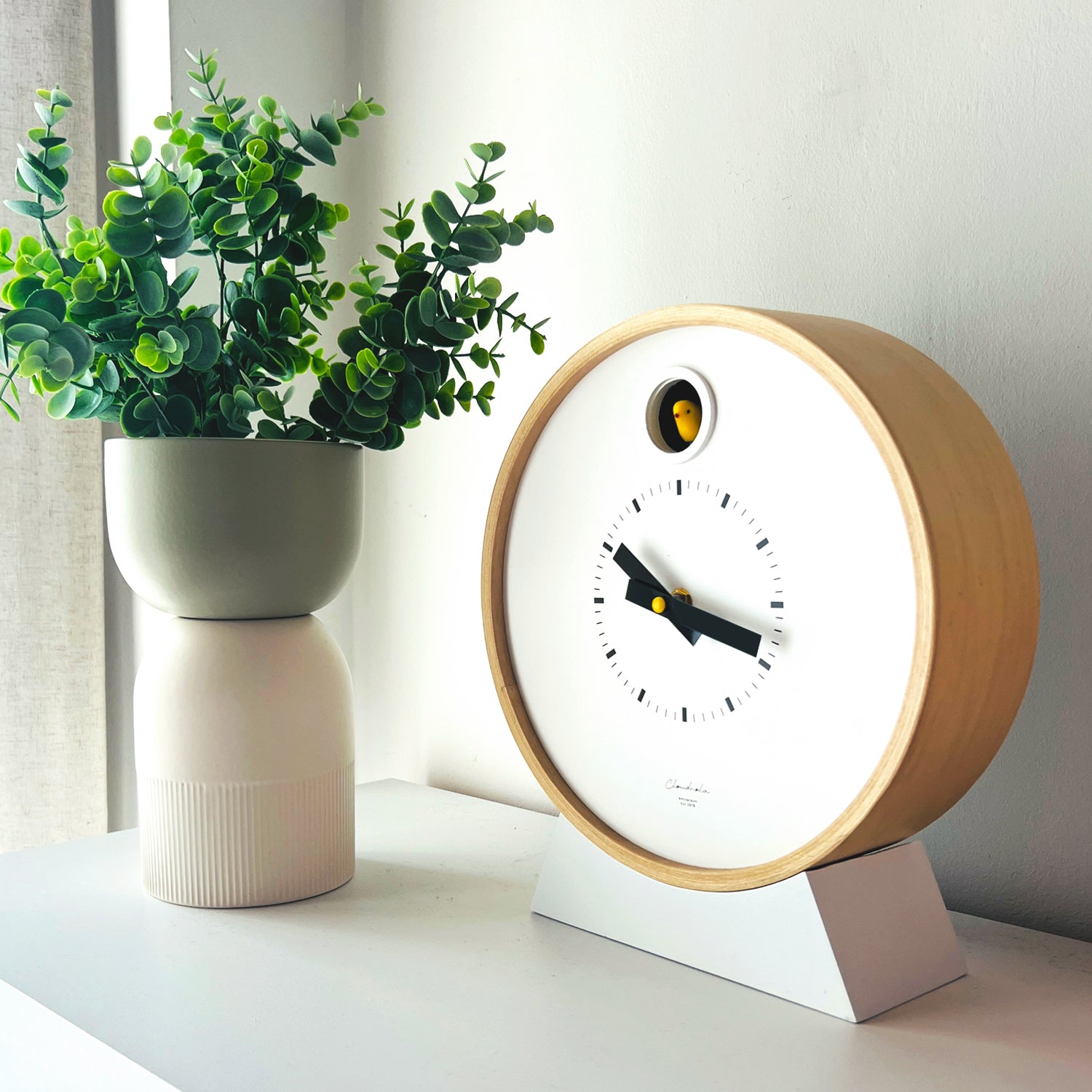 Flip Reversible Ceramic Vase – Ivory & Olive Medium next to a modern minimalist clock in natural light Dutch Design Functional Design