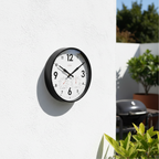 Factory Black Outdoor Clock on white wall in bright garden setting showcasing Dutch Design and Functional Design style