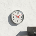 Wall clock with temperature and humidity indicators on a white wall.