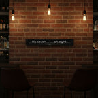 Preorder - Texttime 2.0 BonB Text Flip Clock displayed on brick wall with warm lighting, Dutch Design, Functional Design.